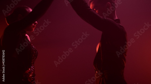 Dancers performing latin dance red light background. Ballroom couple dancing.