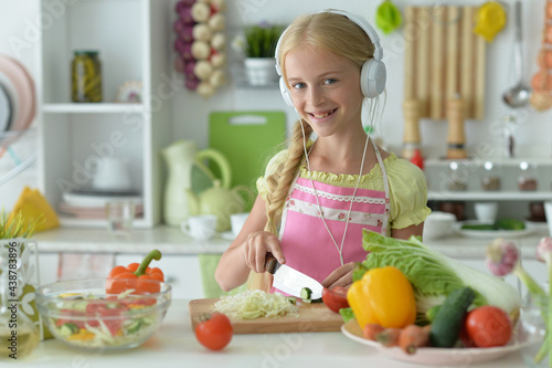beautiful girl in headphones coocking on kitchen