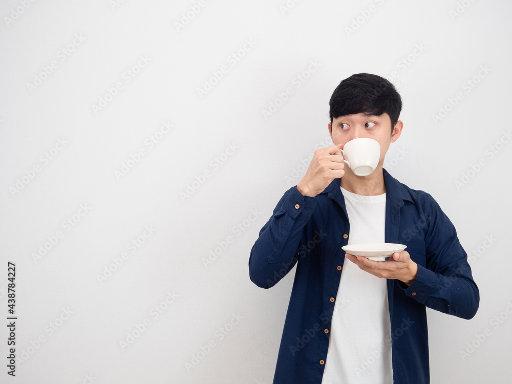 Handsome man drinking coffee cup and looking at copy space side on white background Handsome man drinking coffee cup and looking at copy space side on white background