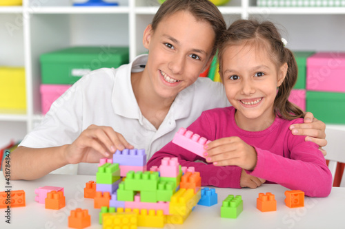 Brother and sister playing with colorful plastic blocks together