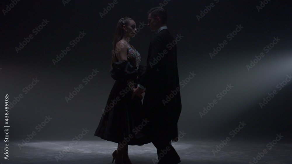Tender ballroom dancers standing on stage. Beautiful dance couple joining hands