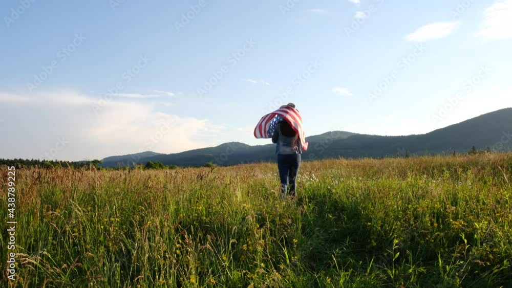 Beautiful young woman 20s in hat walking on green grass holds proudly usa flag high in air, demonstrates patriotism and freedom, excited for summer adventures and holidays, youth, millennial hipster Beautiful young woman 20s in hat walking on green grass holds proudly usa flag high in air, demonstrates patriotism and freedom, excited for summer adventures and holidays, youth, millennial hipster