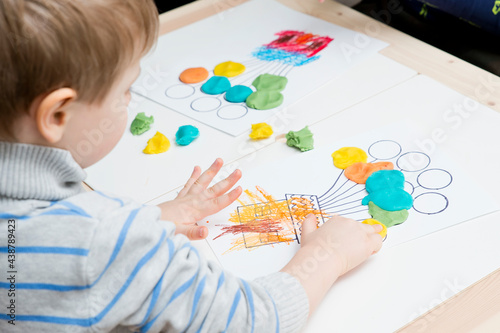 Two pairs of children hands coloring drawing of house with balloons with colored wax crayons. exercise for hand-eye coordination, stimulate imagination, creativity, develop fine motoric skills.