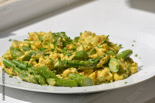 Breakfast eggs with asparagus and chives on a white plate and white background