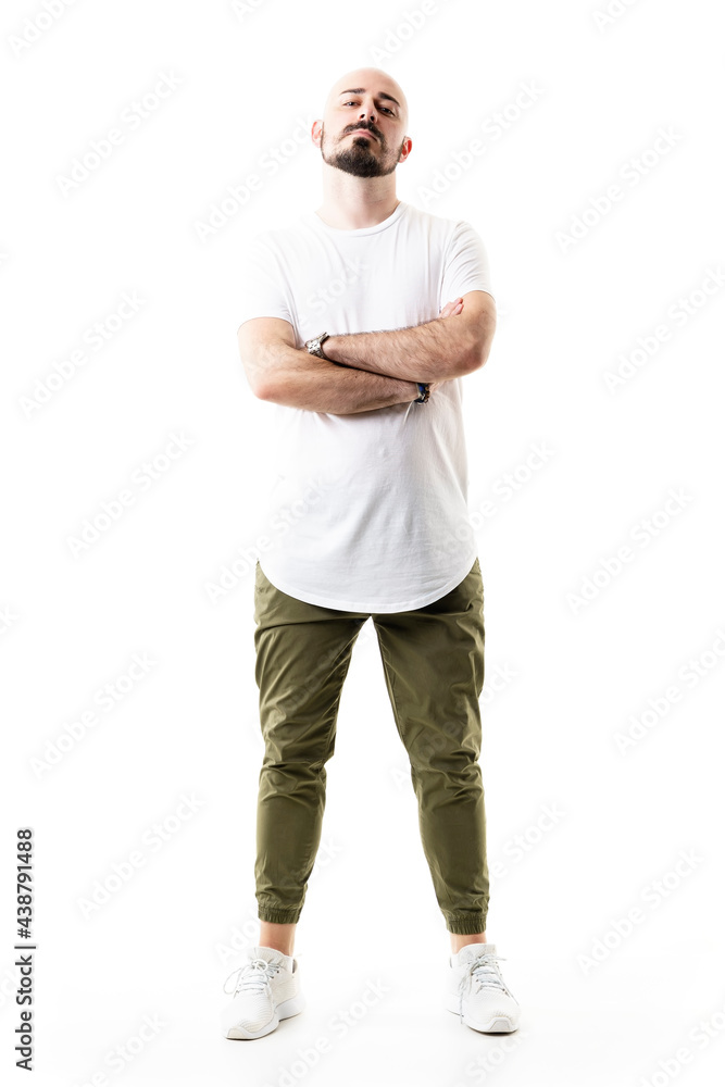 Confident attitude serious bald bearded young man with crossed arms looking at camera. Full body length isolated on white background Confident attitude serious bald bearded young man with crossed arms looking at camera. Full body length isolated on white background
