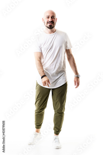 Joyful relaxed young bald stylish man dancing and moving wearing white t-shirt. Full body length isolated on white background