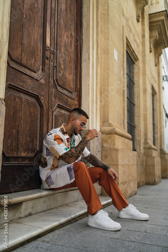 Chico joven guapo tatuado posando en entornos urbanos con ropa a la moda