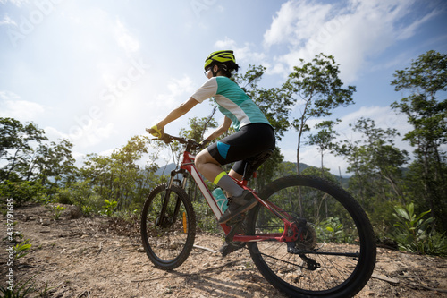 Fototapeta Naklejka Na Ścianę i Meble -  Woman cyclist cycling on mountain top forest trail