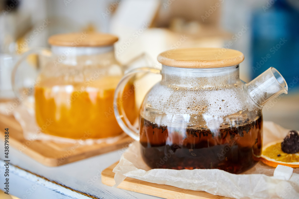 Black tea and Sea buckthorn tea in a transparent glass teapots. Close-up, selective focus