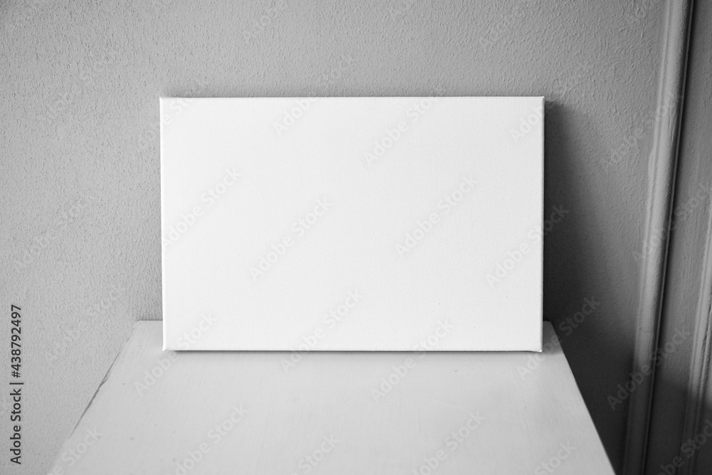 White canvas mockup, blank picture on wooden table in interior with grey wall White canvas mockup, blank picture on wooden table in interior with grey wall