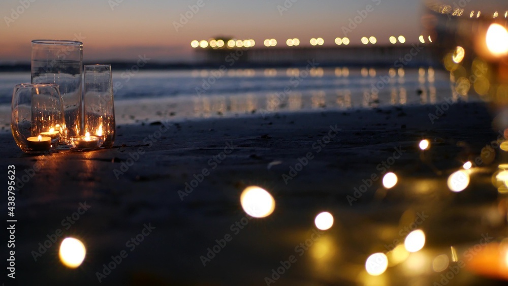 Candle flame lights in glass, romantic beach date, California ocean