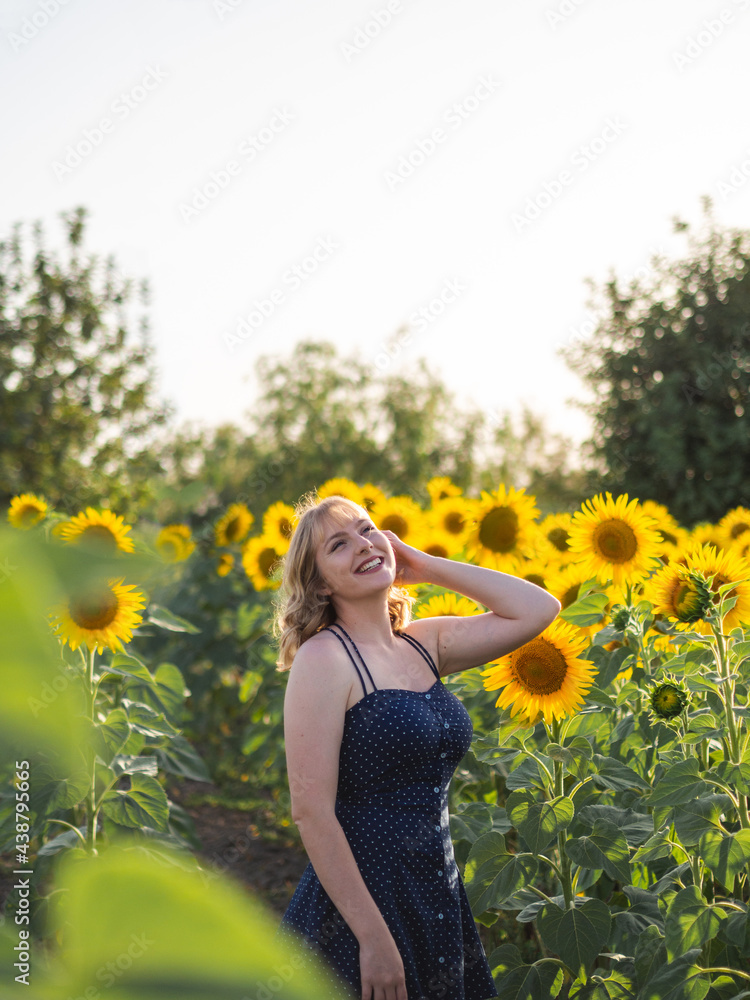 Mujer joven guapa disfrutando de las flores en un campo de girasoles Mujer joven guapa disfrutando de las flores en un campo de girasoles