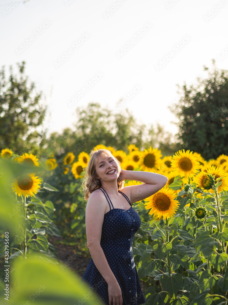 Mujer joven guapa disfrutando de las flores en un campo de girasoles Mujer joven guapa disfrutando de las flores en un campo de girasoles