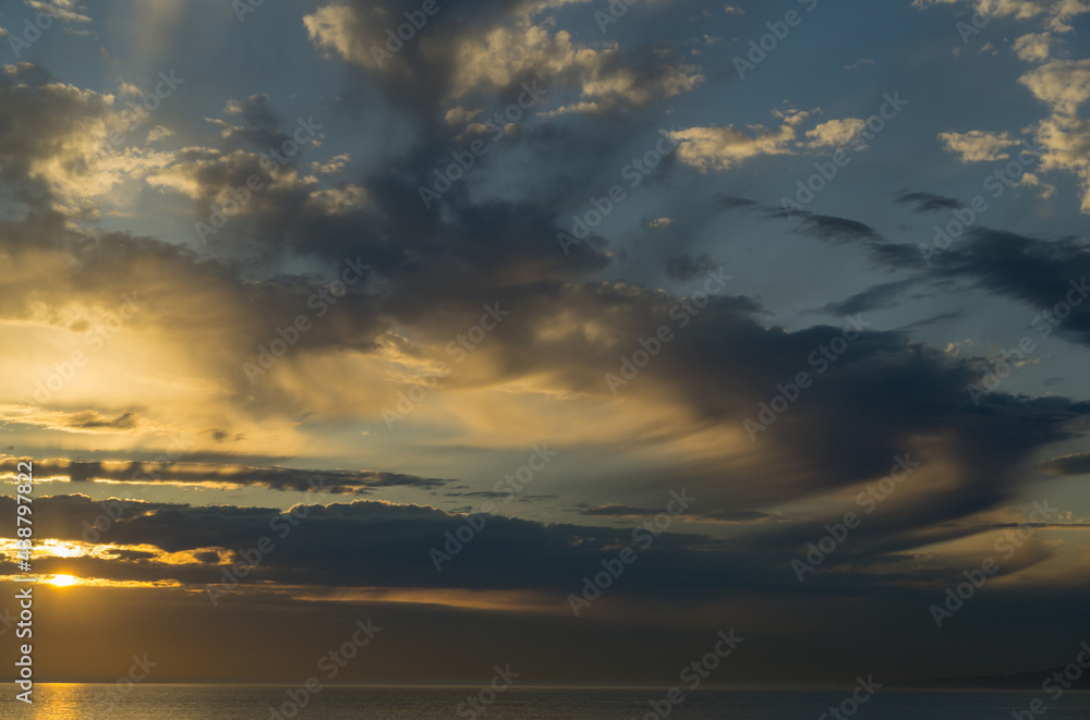 Beautiful sea landscape with sunset on the horizon. Sochi, Black Sea coast of south of Russia. Scenic sky with clouds over the golden water of Black sea. Luxury clouds and natural sky background