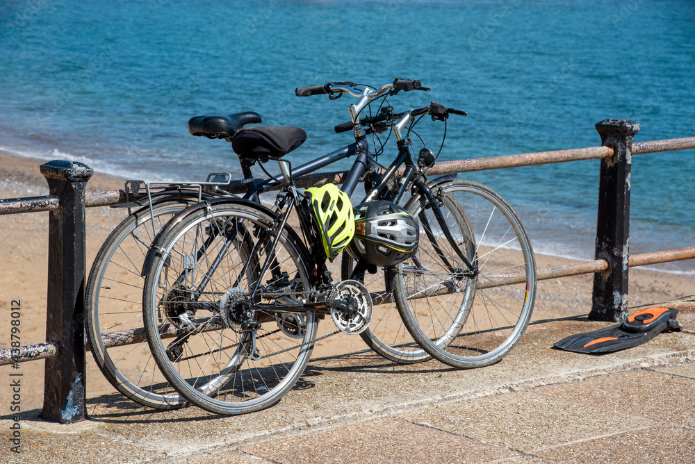 Freshwater Bay, Isle of Wight, UK. 2021. Cycles locked to the seawall barrier above the beach at Freshwater bay, Isle of Wight, UK Freshwater Bay, Isle of Wight, UK. 2021. Cycles locked to the seawall barrier above the beach at Freshwater bay, Isle of Wight, UK