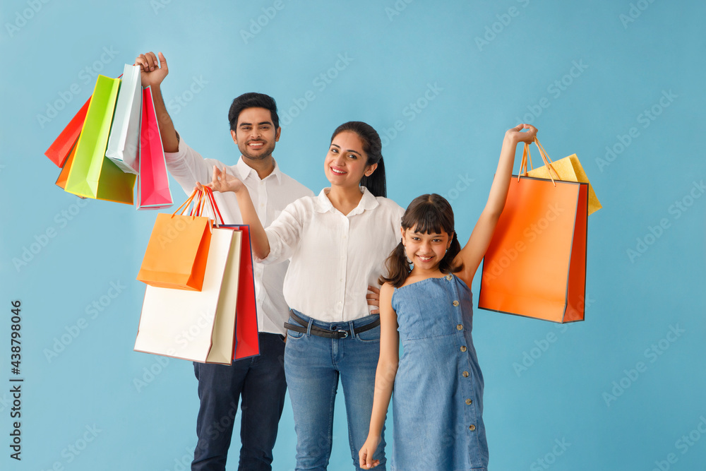 A HAPPY FAMILY PLAYFULLY POSING IN FRONT OF CAMERA WITH SHOPPING BAGS A HAPPY FAMILY PLAYFULLY POSING IN FRONT OF CAMERA WITH SHOPPING BAGS