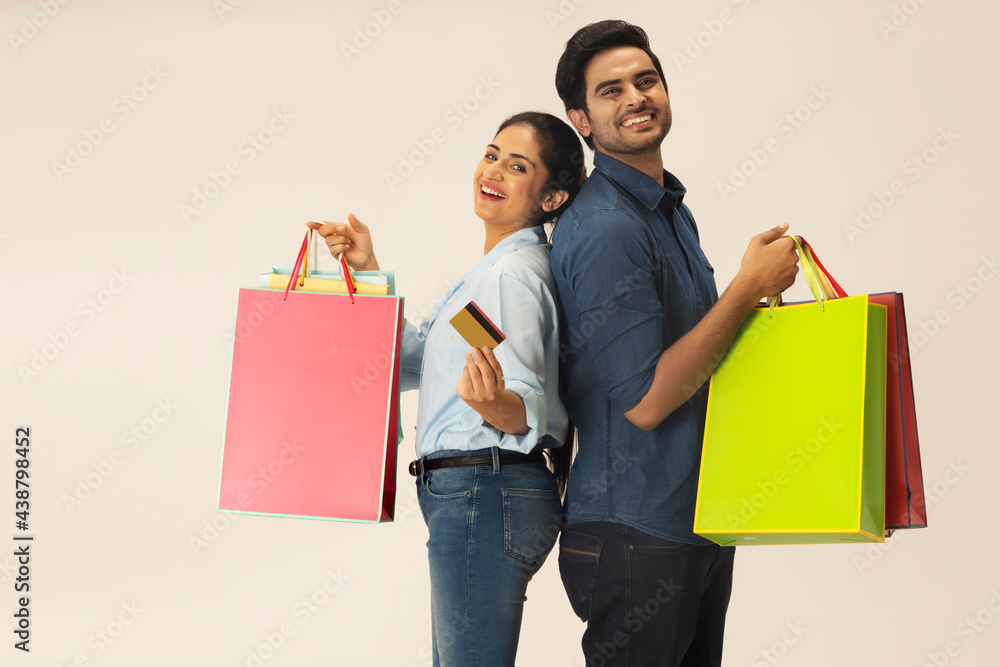 A HAPPY COUPLE POSING TOGETHER WITH SHOPPING BAGS IN HAND A HAPPY COUPLE POSING TOGETHER WITH SHOPPING BAGS IN HAND
