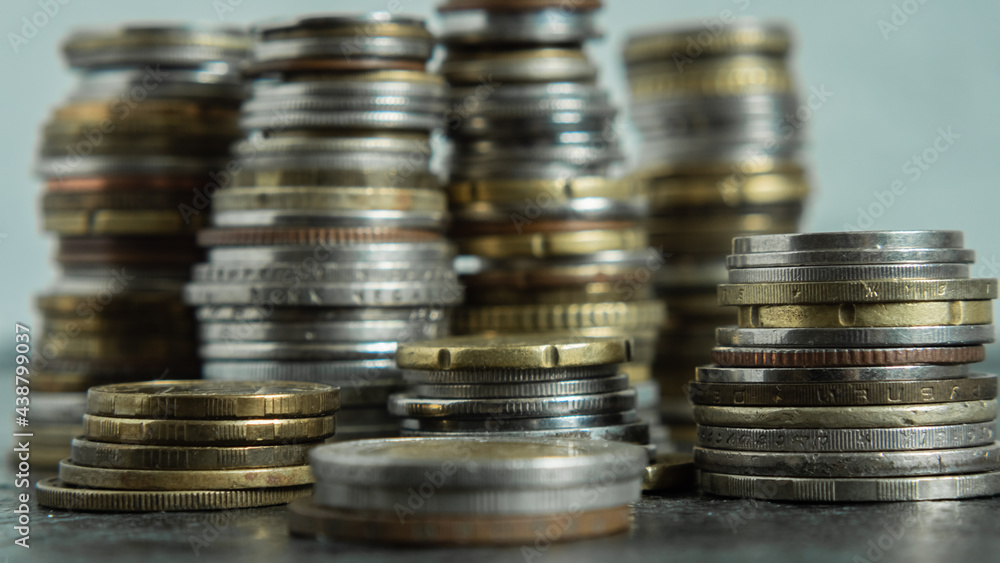 Coins from different countries are stacked in piles of different heights on a black background. Selective focus Coins from different countries are stacked in piles of different heights on a black background. Selective focus