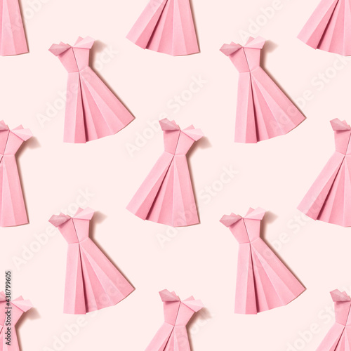 Origami paper background with pink dresses on pink background. Handmadepink dresses backdrop. Origami composition. Paper craft.
