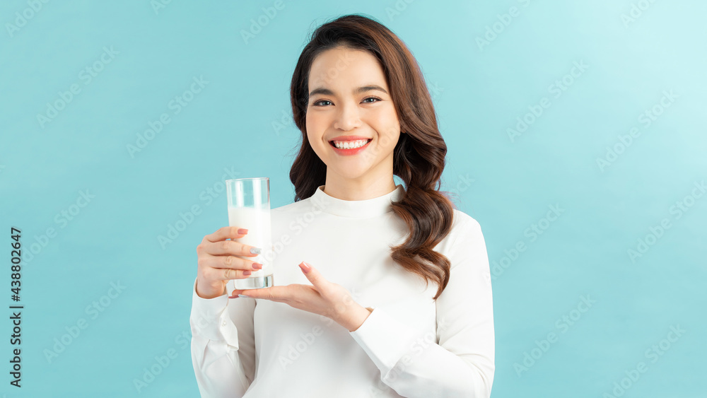 Portrait young asian woman drinking milk from the glass isolated over blue background Portrait young asian woman drinking milk from the glass isolated over blue background