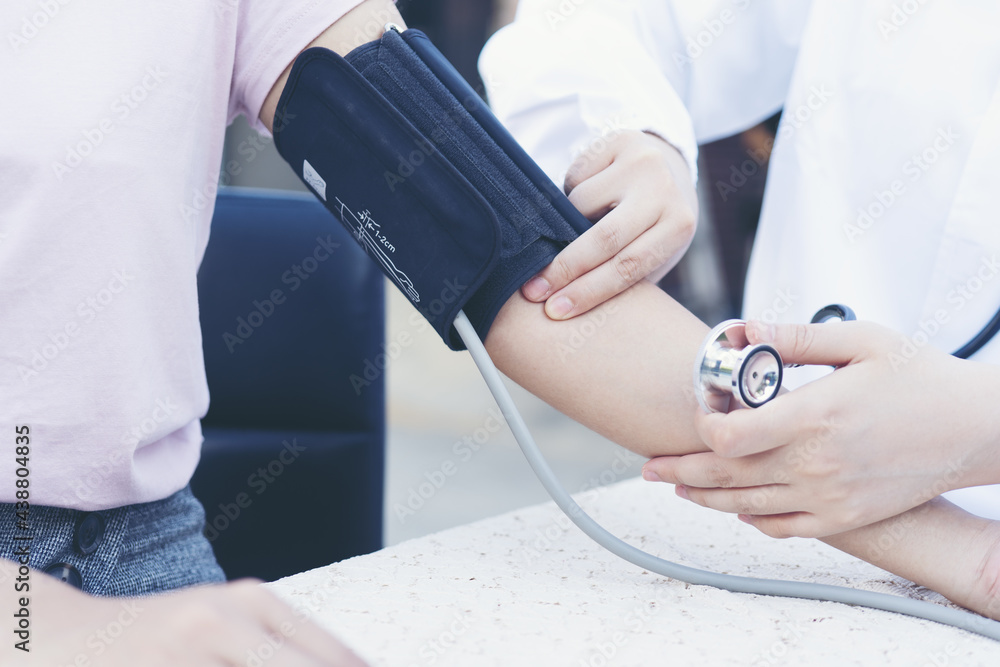 Obraz premium Female doctor holding back to measure patient's blood pressure