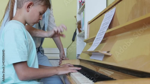 Young Boy Learning To Play Piano Having Lesson From Female Teacher