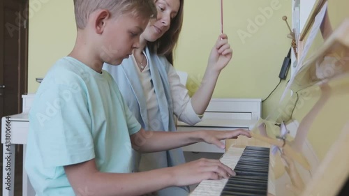 Young Boy Learning To Play Piano Having Lesson From Female Teacher