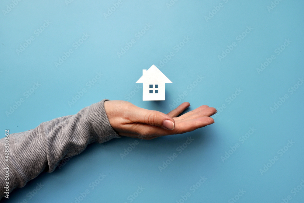 A man holds a paper house in his hand. The symbol of the purchase of housing A man holds a paper house in his hand. The symbol of the purchase of housing