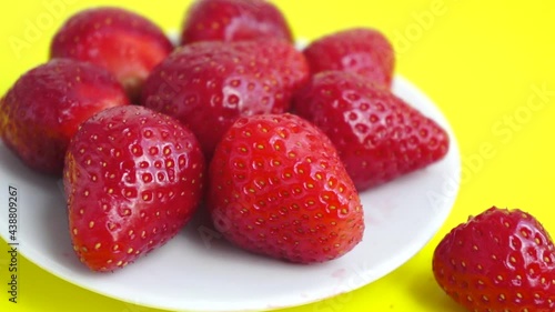 Red strawberry on yellow background close up spinning