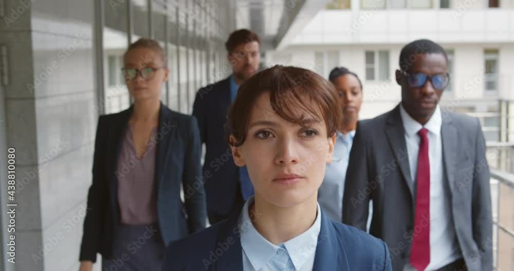 Group of business people and their leader walking outside office building Group of business people and their leader walking outside office building