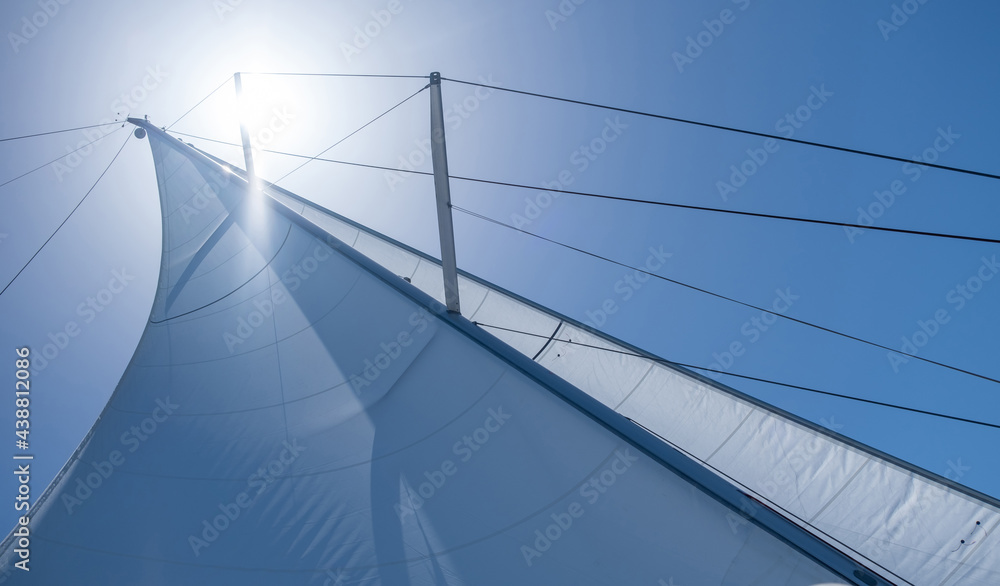 Obraz premium Yacht sails on clear blue sky background. Sailing with the wind at open sea ocean, summer holidays