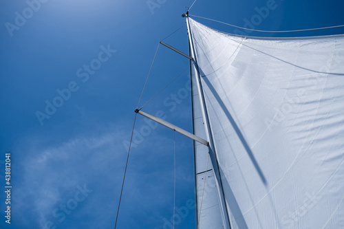 Yacht sails on clear blue sky background. Sailing with the wind at open sea ocean, summer holidays