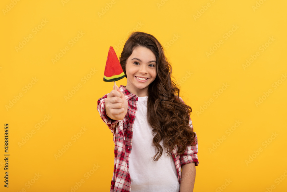 happy child with long curly hair show lollipop caramel candy on yellow background, dental care. happy child with long curly hair show lollipop caramel candy on yellow background, dental care.