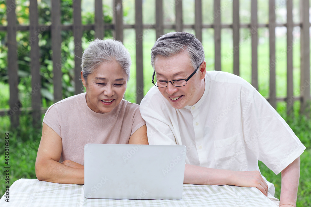 Happy old couple use computer to surf the Internet outdoors Happy old couple use computer to surf the Internet outdoors
