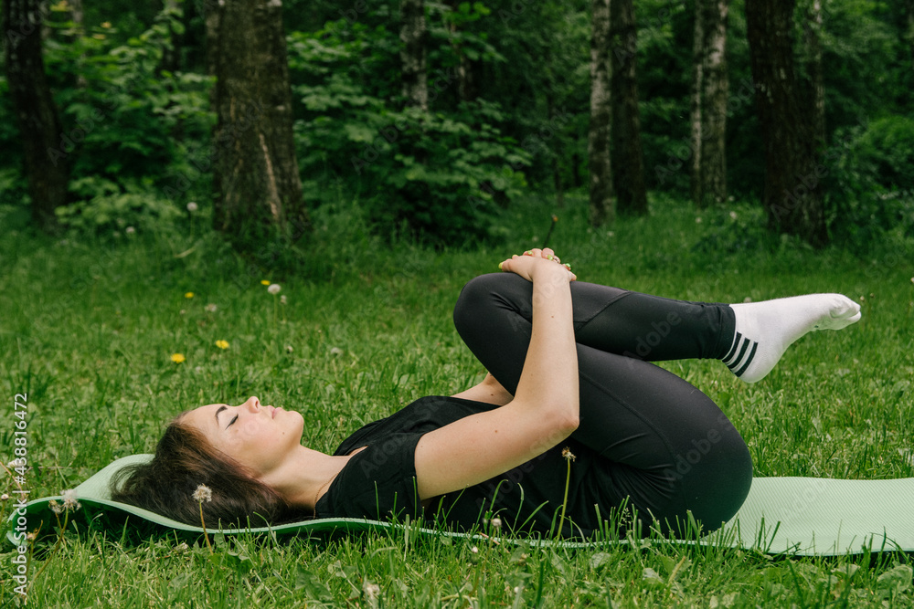 girl in a black t-shirt and leggings shakes the press on a green rug outdoors girl in a black t-shirt and leggings shakes the press on a green rug outdoors