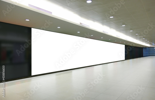 Extreme horizontal long format of blank advertising billboard poster template in a long tunnel walkway; out-of-home OOH media display space mockup in pedestrian linkway; digital display.
