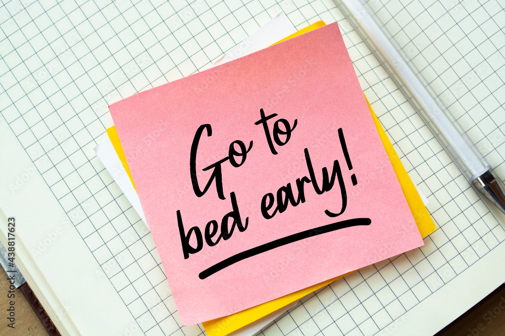 Closeup Pink Sticky Note paste it in a notebook setting an appointment. The words Go to bed early written on a white notebook to remind you an important appointment. Closeup Pink Sticky Note paste it in a notebook setting an appointment. The words Go to bed early written on a white notebook to remind you an important appointment.