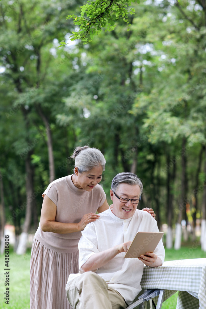 Happy elderly couples use tablet computers to surf the Internet outdoors Happy elderly couples use tablet computers to surf the Internet outdoors