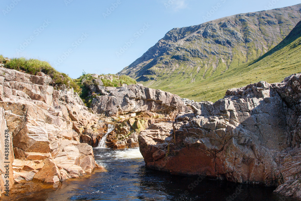 Beautiful Glencoe with a stream and blue sky background on a sunny summers day - Scotland