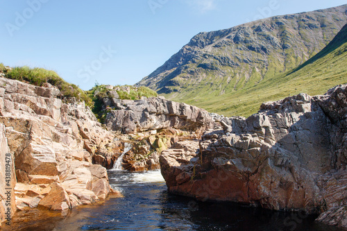 Beautiful Glencoe with a stream and blue sky background on a sunny summers day - Scotland