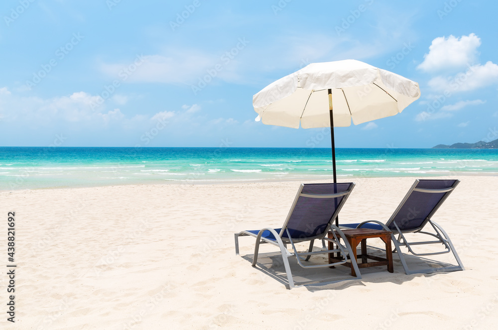 Beach chairs with white umbrella and beautiful sand beach in Koh Samui, Thailand.