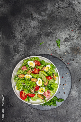 Healthy salad with mussels, quail, egg, conjugate, lime, spinach, lettuce, cherry tomatoes and microgreen. Keto lunch diet. place for text, vertical image. top view