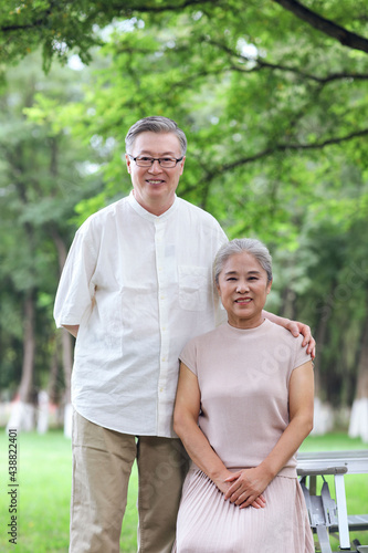 Happy old couple sitting on chairs in outdoor park