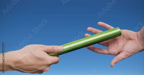 Composition of caucasian athletes passing green relay baton over blue background