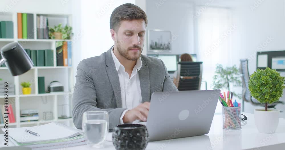 Young millennial professional using computer at home office desk Focused business man entrepreneur typing on laptop doing research. Busy worker freelancer working on modern tech notebook device. Young millennial professional using computer at home office desk Focused business man entrepreneur typing on laptop doing research. Busy worker freelancer working on modern tech notebook device.
