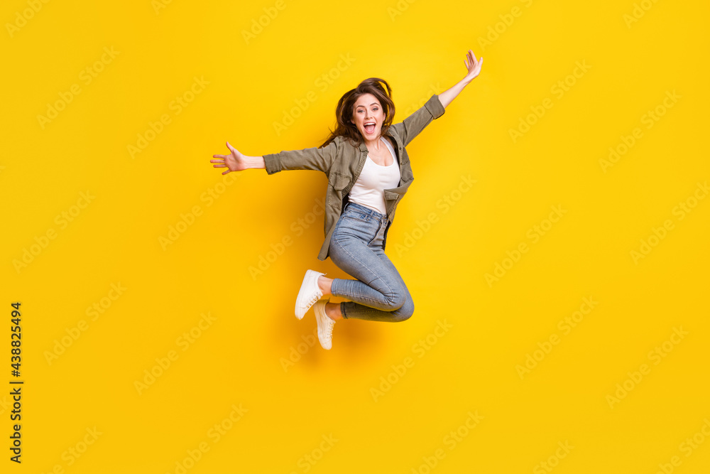 Full length body size view of attractive cheerful girl jumping having fun success isolated over bright yellow color background Full length body size view of attractive cheerful girl jumping having fun success isolated over bright yellow color background