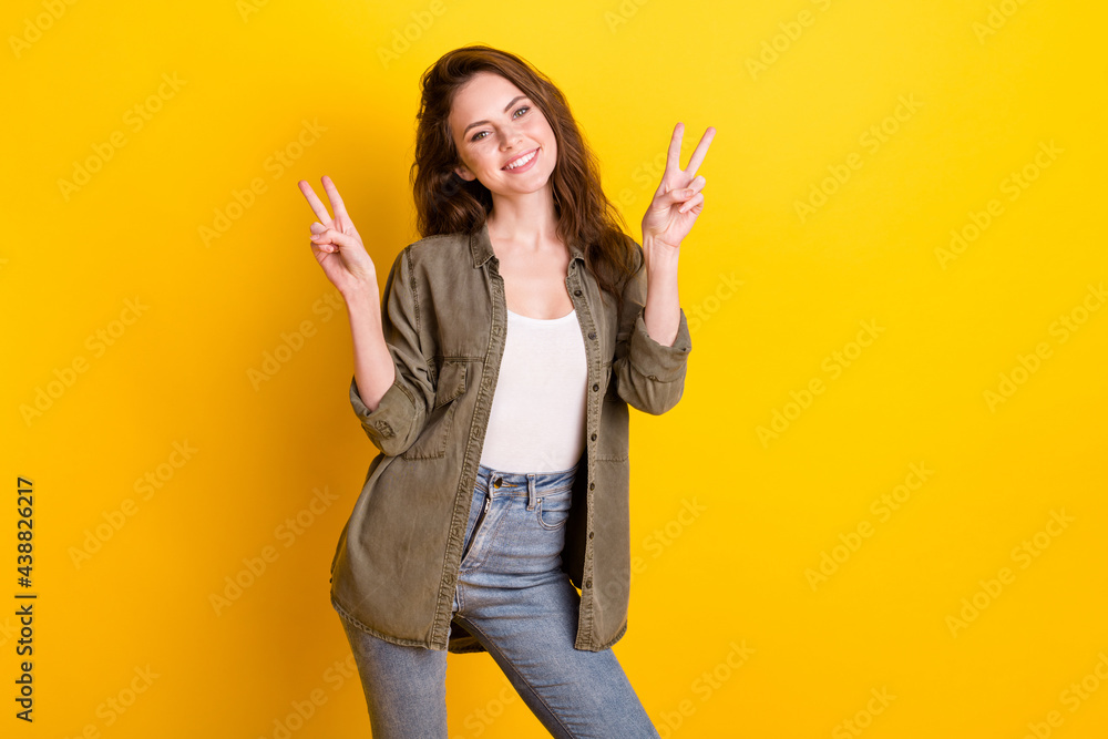 Photo of adorable satisfied person two hands fingers show v-sign toothy smile isolated on yellow color background Photo of adorable satisfied person two hands fingers show v-sign toothy smile isolated on yellow color background