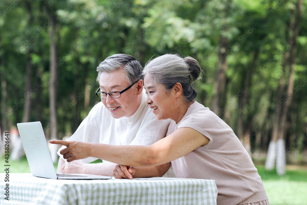 Happy old couple use computer to surf the Internet outdoors Happy old couple use computer to surf the Internet outdoors