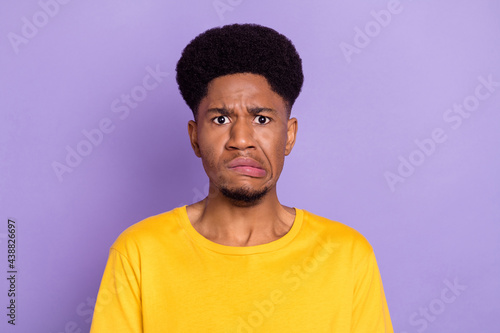 Portrait of attractive moody confused guy bad mood grimacing isolated over violet purple color background