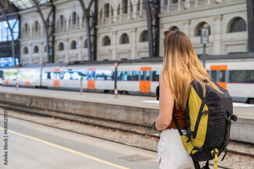 Young woman with backpack waiting at train station platform